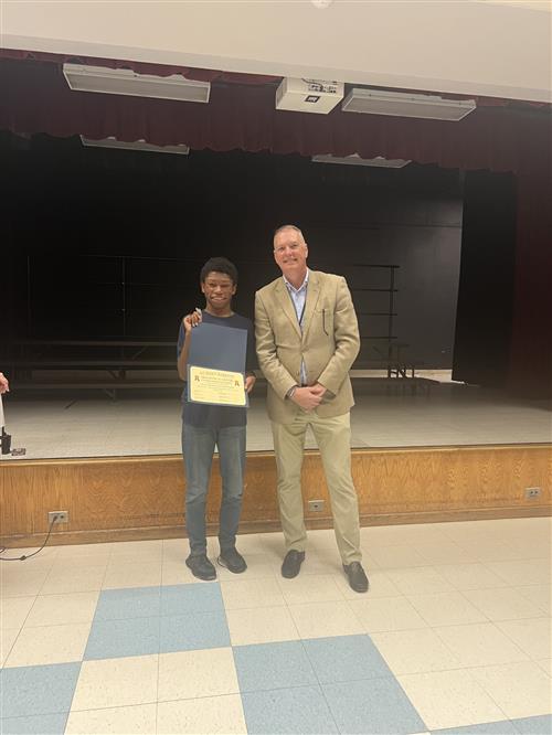 Tra'maine H. poses with his award and the District Superintendent.